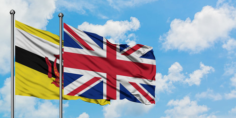 Brunei and United Kingdom flag waving in the wind against white cloudy blue sky together. Diplomacy concept, international relations.