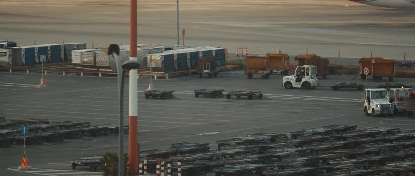 Man driving a small service baggage car on a runway of the airport at sunset, BMPCC 4K - cinematic slow motion. Smooth movement, handled, long shot.