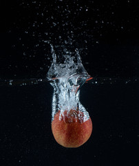 Manzana cayendo en el agua sobre fondo negro