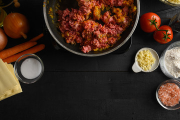 cooking Italian lasagna, preparing dressing for lasagna with ground beef and vegetables, Italian cuisine. Roasting in a pan, black background for design. Recipe book, menu, restaurant, Top view