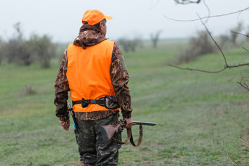 Hunting period, autumn season open. A hunter with a gun in his hands in hunting clothes in the...