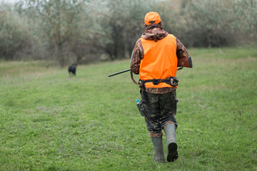 Hunting period, autumn season open. A hunter with a gun in his hands in hunting clothes in the...
