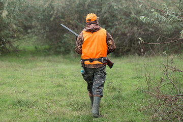 Hunting period, autumn season open. A hunter with a gun in his hands in hunting clothes in the...