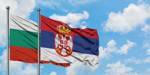 Bulgaria and Serbia flag waving in the wind against white cloudy blue sky together. Diplomacy concept, international relations.