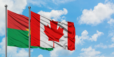 Burkina Faso and Canada flag waving in the wind against white cloudy blue sky together. Diplomacy concept, international relations.