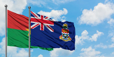 Burkina Faso and Cayman Islands flag waving in the wind against white cloudy blue sky together. Diplomacy concept, international relations.