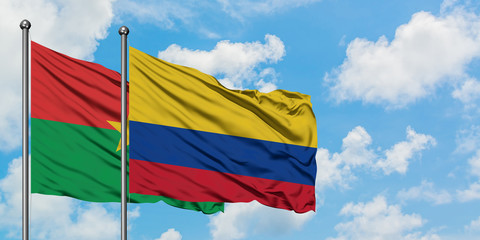Burkina Faso and Colombia flag waving in the wind against white cloudy blue sky together. Diplomacy concept, international relations.