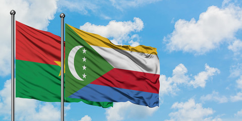 Burkina Faso and Comoros flag waving in the wind against white cloudy blue sky together. Diplomacy concept, international relations.