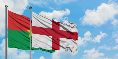 Burkina Faso and England flag waving in the wind against white cloudy blue sky together. Diplomacy concept, international relations.