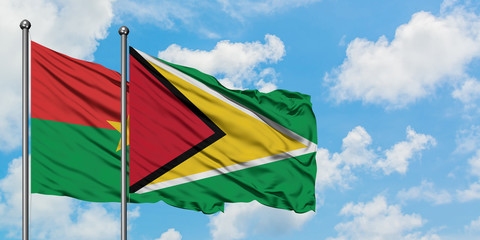 Burkina Faso and Guyana flag waving in the wind against white cloudy blue sky together. Diplomacy concept, international relations.