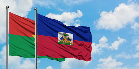 Burkina Faso and Haiti flag waving in the wind against white cloudy blue sky together. Diplomacy...