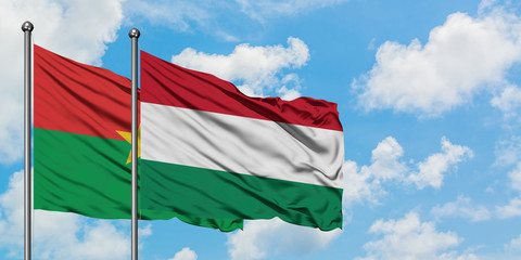 Burkina Faso and Hungary flag waving in the wind against white cloudy blue sky together. Diplomacy concept, international relations.