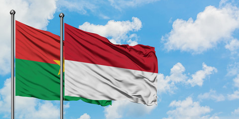 Burkina Faso and Indonesia flag waving in the wind against white cloudy blue sky together. Diplomacy concept, international relations.