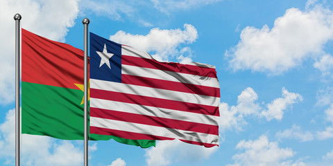 Burkina Faso and Liberia flag waving in the wind against white cloudy blue sky together. Diplomacy concept, international relations.