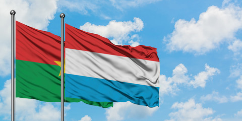 Burkina Faso and Luxembourg flag waving in the wind against white cloudy blue sky together. Diplomacy concept, international relations.