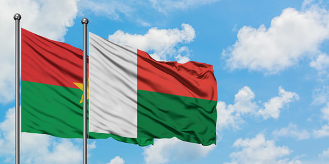 Burkina Faso and Madagascar flag waving in the wind against white cloudy blue sky together. Diplomacy concept, international relations.