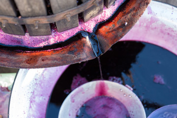 Winepress with red must and helical screw. Traditional old technique of wine making. Filtering grape must.	