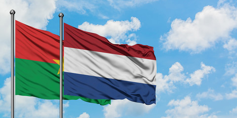 Burkina Faso and Netherlands flag waving in the wind against white cloudy blue sky together. Diplomacy concept, international relations.