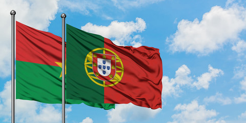 Burkina Faso and Portugal flag waving in the wind against white cloudy blue sky together. Diplomacy concept, international relations.