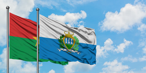 Burkina Faso and San Marino flag waving in the wind against white cloudy blue sky together. Diplomacy concept, international relations.