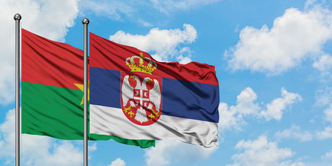 Burkina Faso and Serbia flag waving in the wind against white cloudy blue sky together. Diplomacy concept, international relations.