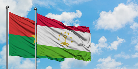 Burkina Faso and Tajikistan flag waving in the wind against white cloudy blue sky together. Diplomacy concept, international relations.