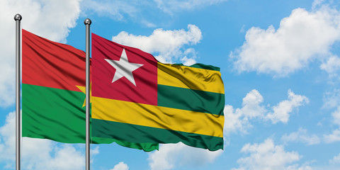 Burkina Faso and Togo flag waving in the wind against white cloudy blue sky together. Diplomacy concept, international relations.