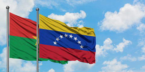 Burkina Faso and Venezuela flag waving in the wind against white cloudy blue sky together. Diplomacy concept, international relations.