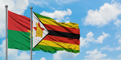 Burkina Faso and Zimbabwe flag waving in the wind against white cloudy blue sky together. Diplomacy concept, international relations.