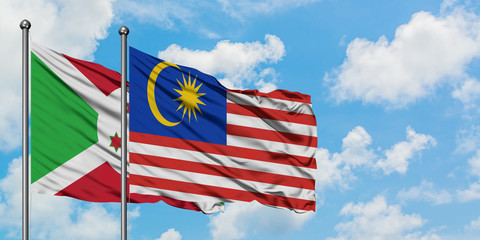 Burundi and Malaysia flag waving in the wind against white cloudy blue sky together. Diplomacy concept, international relations.