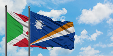 Burundi and Marshall Islands flag waving in the wind against white cloudy blue sky together. Diplomacy concept, international relations.