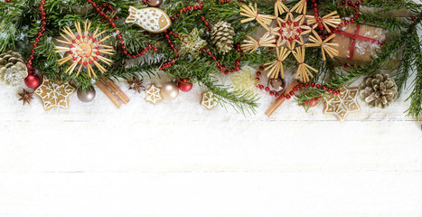 Naklejka na ściany i meble Christmas border with fir tree branches, straw stars, baubles and decoration on white pained wood in panoramic format, copy space, high angle top view from above