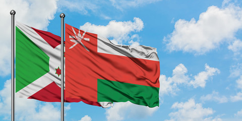 Burundi and Oman flag waving in the wind against white cloudy blue sky together. Diplomacy concept, international relations.