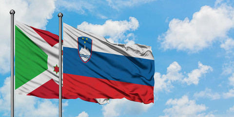 Burundi and Slovenia flag waving in the wind against white cloudy blue sky together. Diplomacy concept, international relations.
