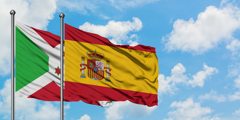 Burundi and Spain flag waving in the wind against white cloudy blue sky together. Diplomacy concept, international relations.