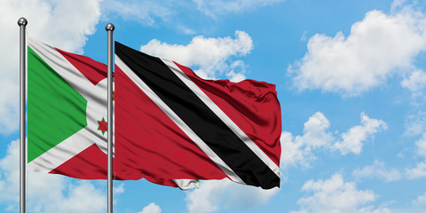 Burundi and Trinidad And Tobago flag waving in the wind against white cloudy blue sky together. Diplomacy concept, international relations.