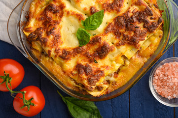 Italian lasagna, on a blue wooden background. Culinary background, Italian recipe book, delicious food. With space for design, top view.