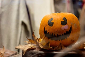 Orange big pumpkin with viburnum on top with a black marker drawing, white fangs, halloween in a shopping center close-up