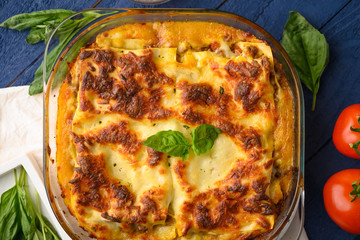 Italian lasagna, on a blue wooden background. Culinary background, Italian recipe book, delicious food. With space for design, top view.