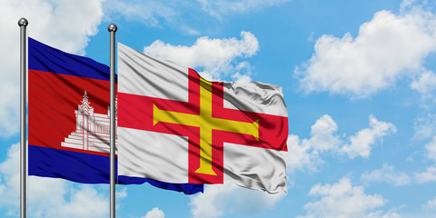 Cambodia and Guernsey flag waving in the wind against white cloudy blue sky together. Diplomacy concept, international relations.