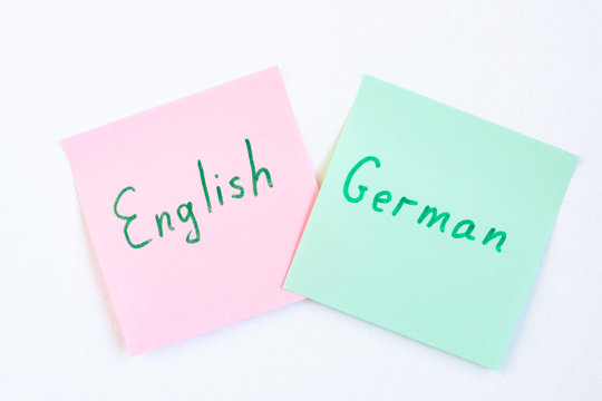 Top view flat lay of two languages english and german which written on the reminder notepaper of different colors