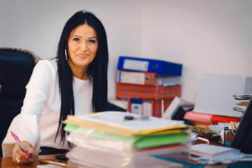 Beautiful woman accountant at her office at the agency working on her computer at the desk on...