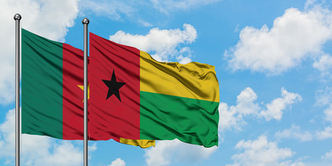 Cameroon and Guinea Bissau flag waving in the wind against white cloudy blue sky together. Diplomacy concept, international relations.