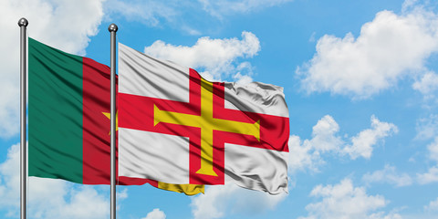 Cameroon and Guernsey flag waving in the wind against white cloudy blue sky together. Diplomacy concept, international relations.