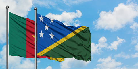 Cameroon and Solomon Islands flag waving in the wind against white cloudy blue sky together. Diplomacy concept, international relations.