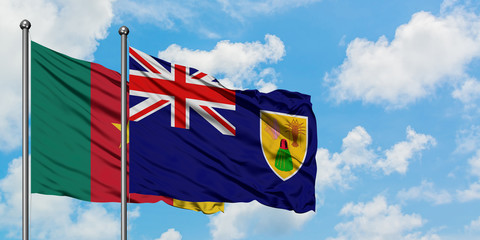 Cameroon and Turks And Caicos Islands flag waving in the wind against white cloudy blue sky together. Diplomacy concept, international relations.
