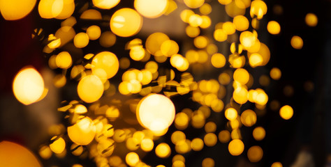 Golden and black bokeh background of garland lights. Christmas holiday and New Year concept. With copy space