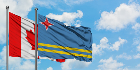 Canada and Aruba flag waving in the wind against white cloudy blue sky together. Diplomacy concept, international relations.