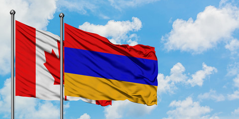 Canada and Armenia flag waving in the wind against white cloudy blue sky together. Diplomacy concept, international relations.