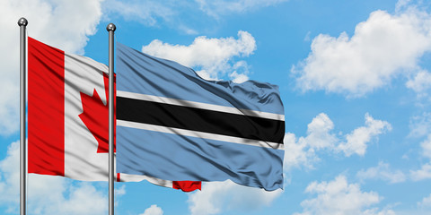 Canada and Botswana flag waving in the wind against white cloudy blue sky together. Diplomacy concept, international relations.